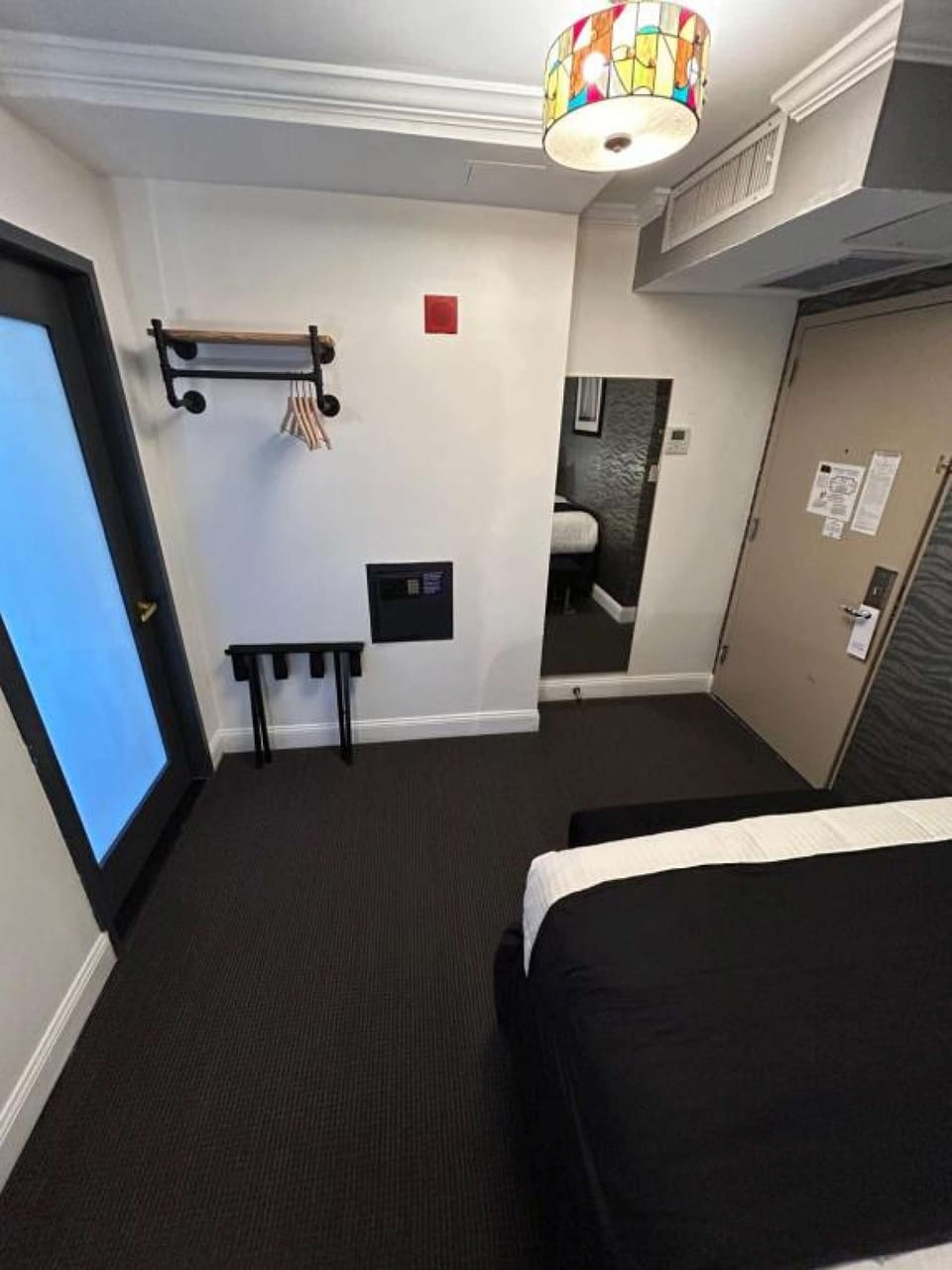 Room with black-and-white bedding, desk station, and wall TV..