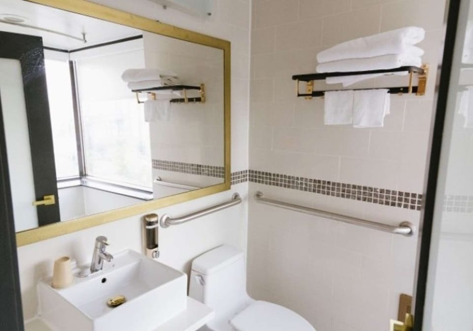 Clean tiled space with large mirror, towel rack, and corner window view.