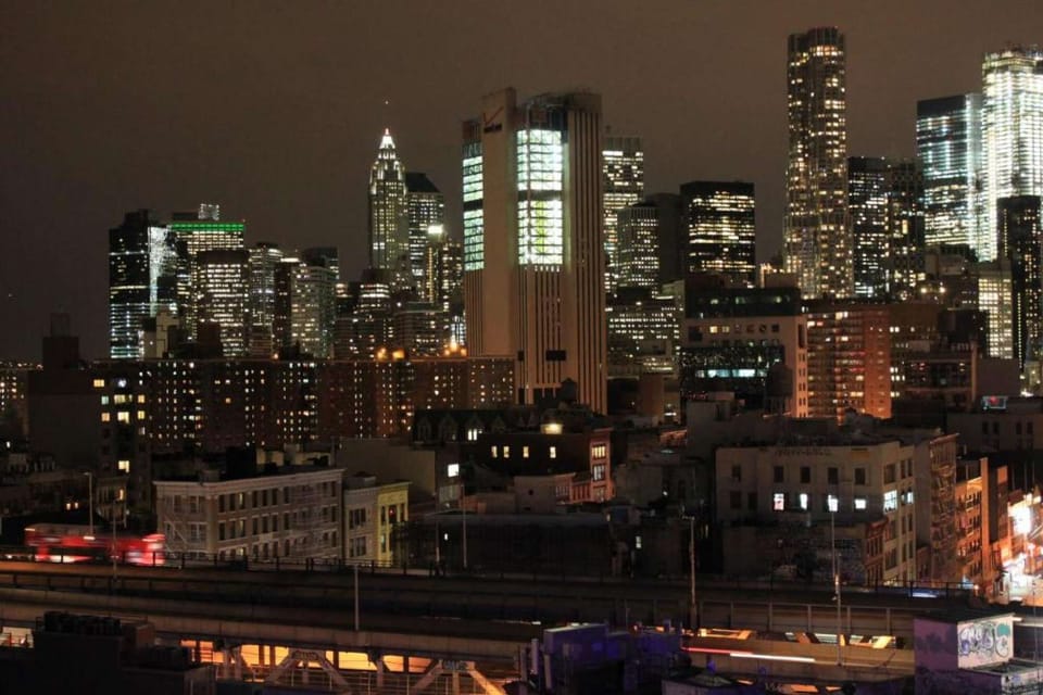 Tall city buildings illuminated after dark with dense lights across windows.
