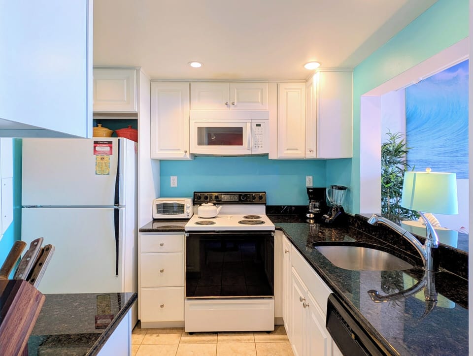 908 Dover Sea Colony East Modern Kitchen - Updated kitchen at 908 Dover, Sea Colony East, featuring white cabinetry, modern appliances, and vibrant coastal blue walls.