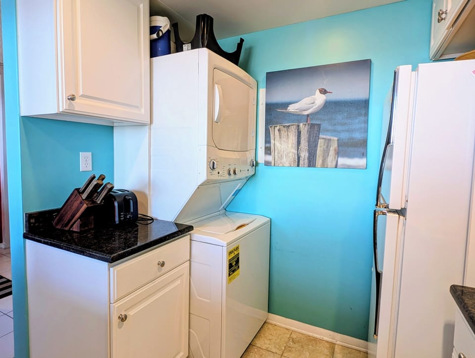908 Dover Sea Colony East Foyer Laundry Room - Welcoming entry Laundry Room at 908 Dover with modern flooring, coastal wall art, and Drawers.