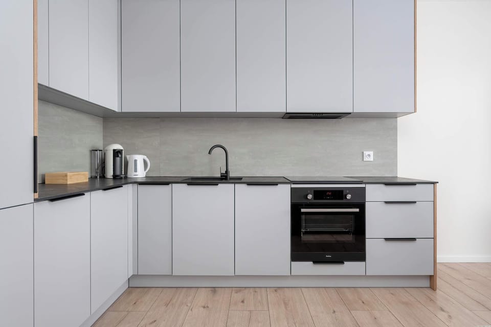A sleek kitchenette with white cabinetry, built-in appliances, and a clean, contemporary layout.