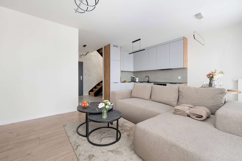 A spacious open-plan living room connecting seating and dining areas in a bright, modern interior.
