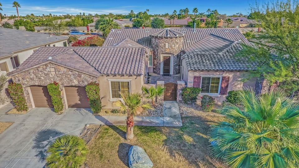 Charming desert-style home with stone accents, palm trees, and beautifully landscaped grounds.