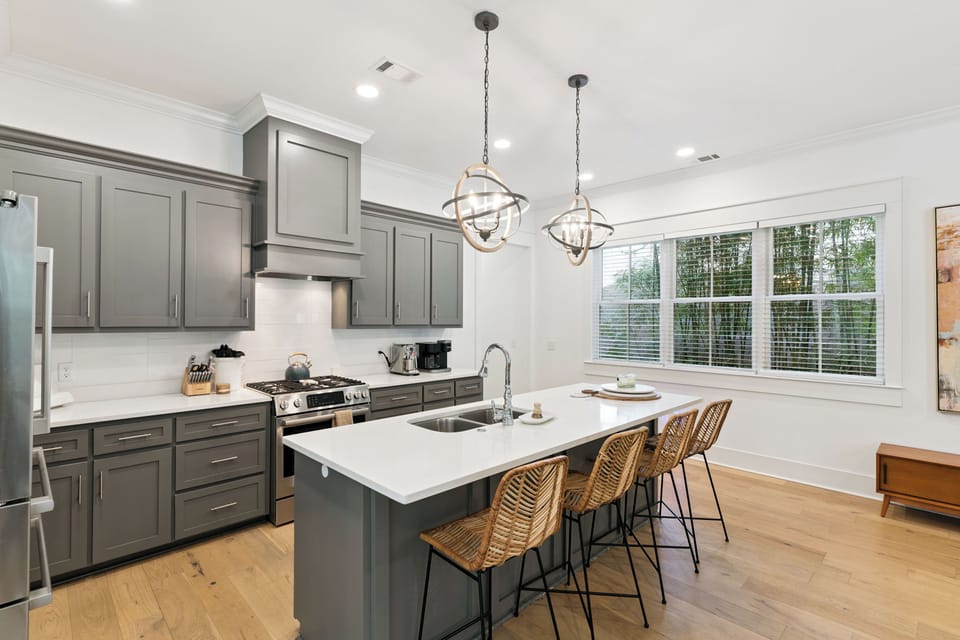 Your dream kitchen awaits with sleek gray cabinetry, pristine white countertops, and warm wood floors perfect for culinary adventures.