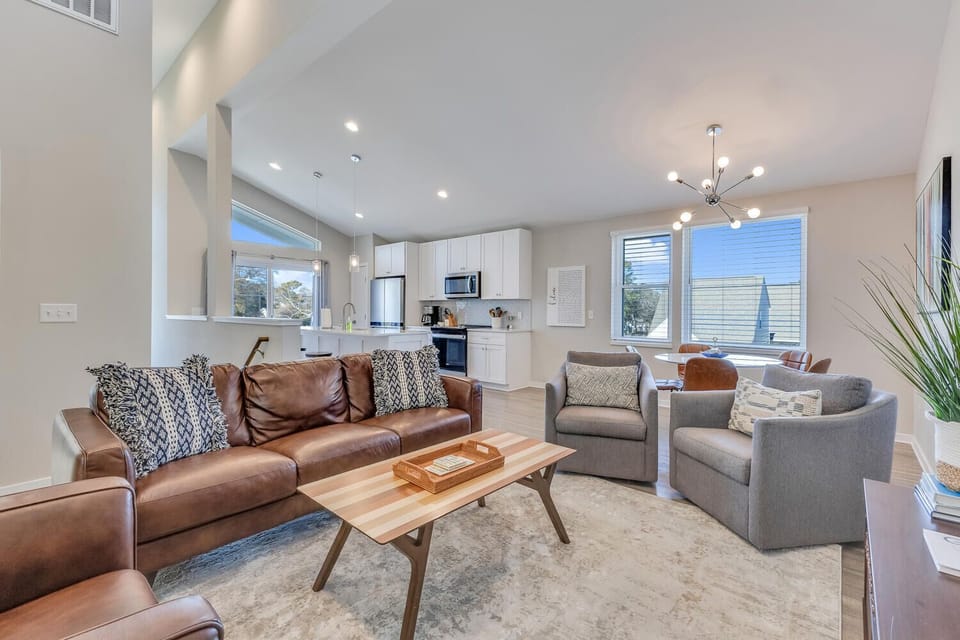 Relax in your stylish open-plan living space with plush leather seating, modern kitchen, and abundant natural light streaming through large windows.