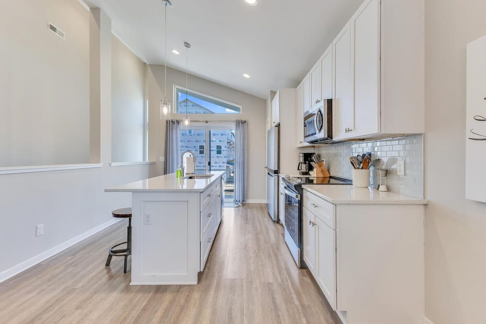 Your fully equipped kitchen features pristine white cabinets, modern appliances, and a convenient island for meal prep.