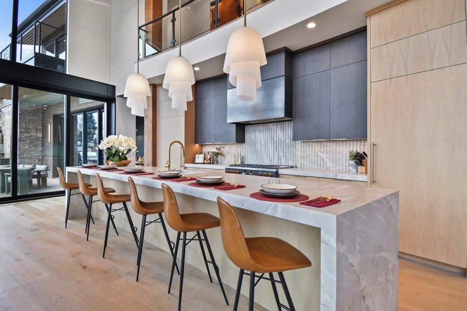 Your modern kitchen awaits with sleek marble island, elegant pendant lighting, and stunning double-height ceilings creating an open, airy cooking experience.