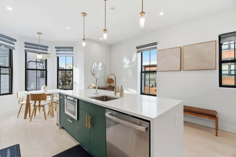 Bright and welcoming kitchen featuring a breakfast bar with stools and a small dining table, offering flexible spaces for meals, coffee, or casual gatherings.