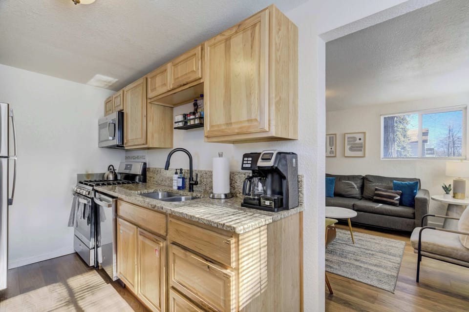 Another angle of the kitchen showcasing the clean layout and connection to the living room, functional work surfaces, and thoughtful organization that make cooking and dining easy during your stay.
