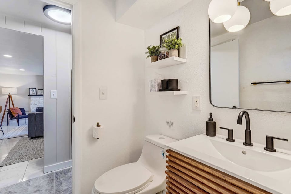 The bathroom features a sleek vanity with matte black fixtures and stylish lighting. Stocked with plush towels and essential toiletries this modern space offers a comfortable and high end experience for your stay.
