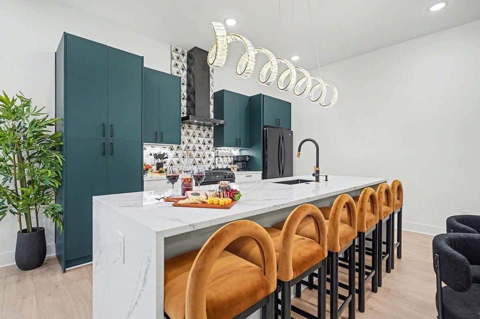 2nd Floor: Fully equipped kitchen with green cabinetry, marble countertops, black appliances, and a striking waterfall island offering bar seating for 6.