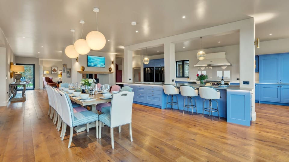 Lit by statement pendant lights above and natural light from the large glass doors, the dining table seats 12.