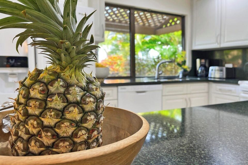 A fresh pineapple centerpiece adds a warm island touch to the kitchen's spacious granite countertop.