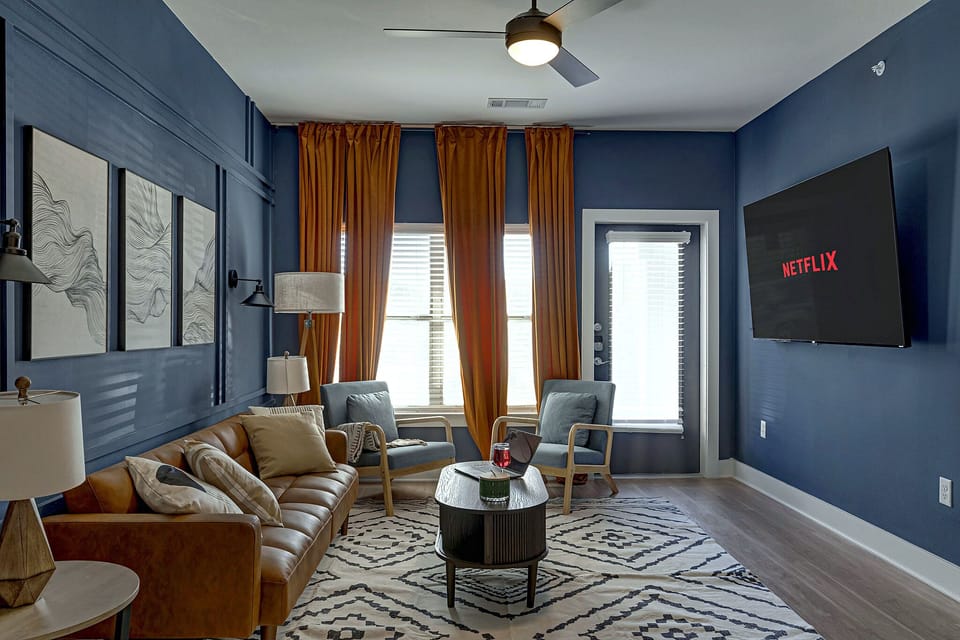 Stylish lounge with bold decor, tall windows, and large TV for cozy nights