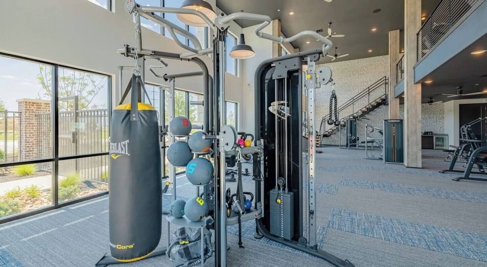 Spacious, sunlit gym with functional trainer, bag, and cardio zone