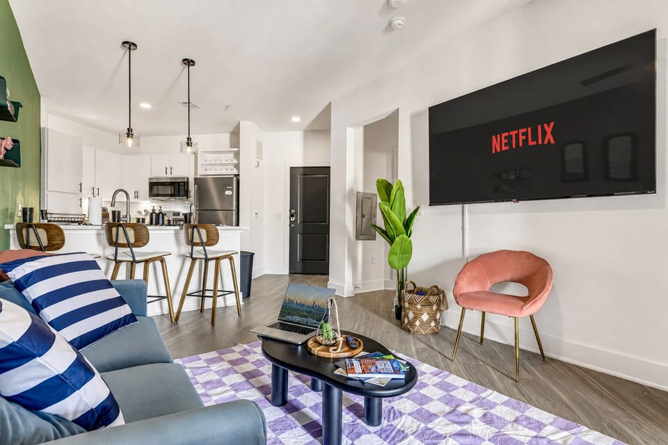 Bright modern living room with big TV, stylish kitchen, and breakfast bar