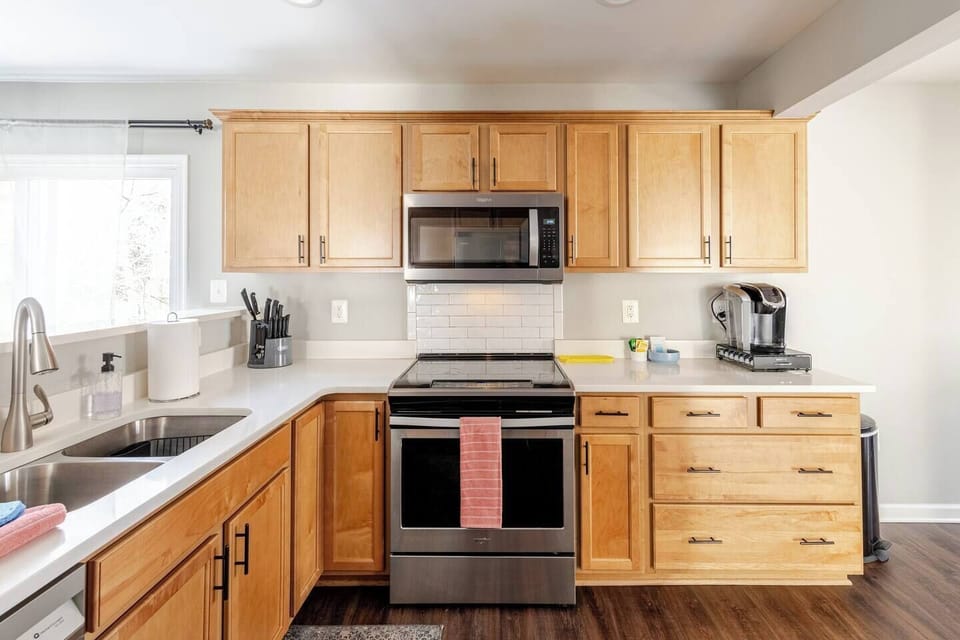 Stainless electric range, microwave, and full-size sink with maple cabinetry