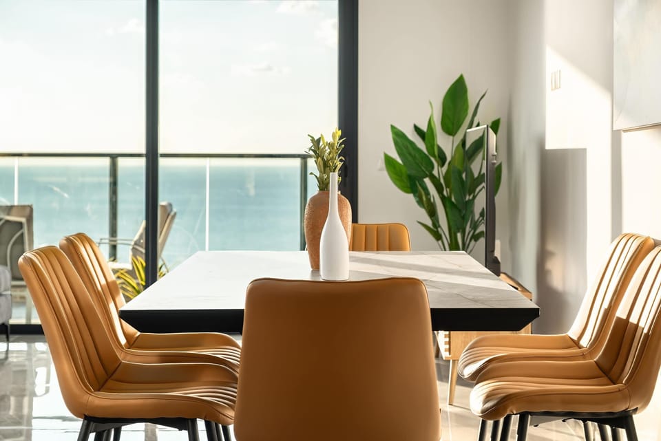 Modern dining setting overlooks the sea, refined chairs elevate every shared meal experience