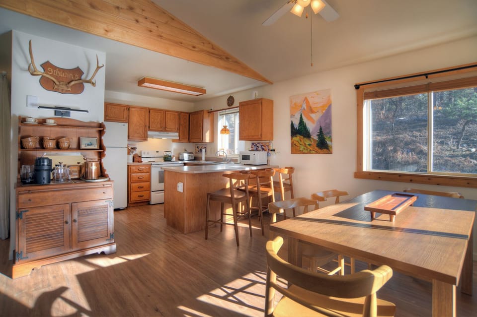 Open-concept kitchen and dining area with vaulted ceilings and mountain views – a warm, inviting space perfect for gathering and preparing home-cooked meals.