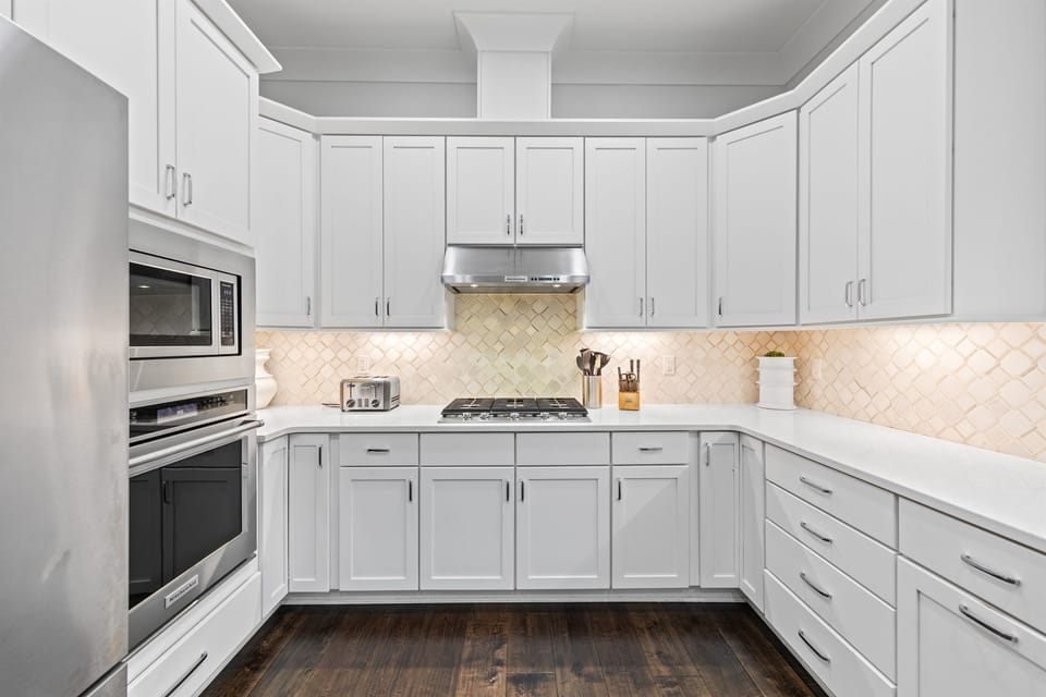 The open, fully stocked kitchen is designed for gathering, featuring abundant natural light, generous counter space, and a large island perfect for serving meals and snacks to big groups. An easy, inviting space where cooking, conversation, and connection 