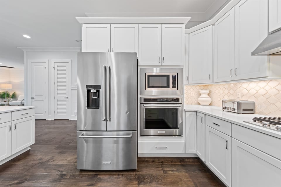 The open, fully stocked kitchen is designed for gathering, featuring abundant natural light, generous counter space, and a large island perfect for serving meals and snacks to big groups. An easy, inviting space where cooking, conversation, and connection 