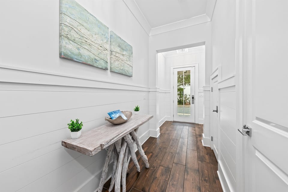 A bright, welcoming entry hallway offering effortless access to the first-floor bedroom, half bath, garage, and pool deck. Designed for smooth arrivals and easy unloading, it sets the tone for relaxed, stress-free coastal living from the moment you arrive.