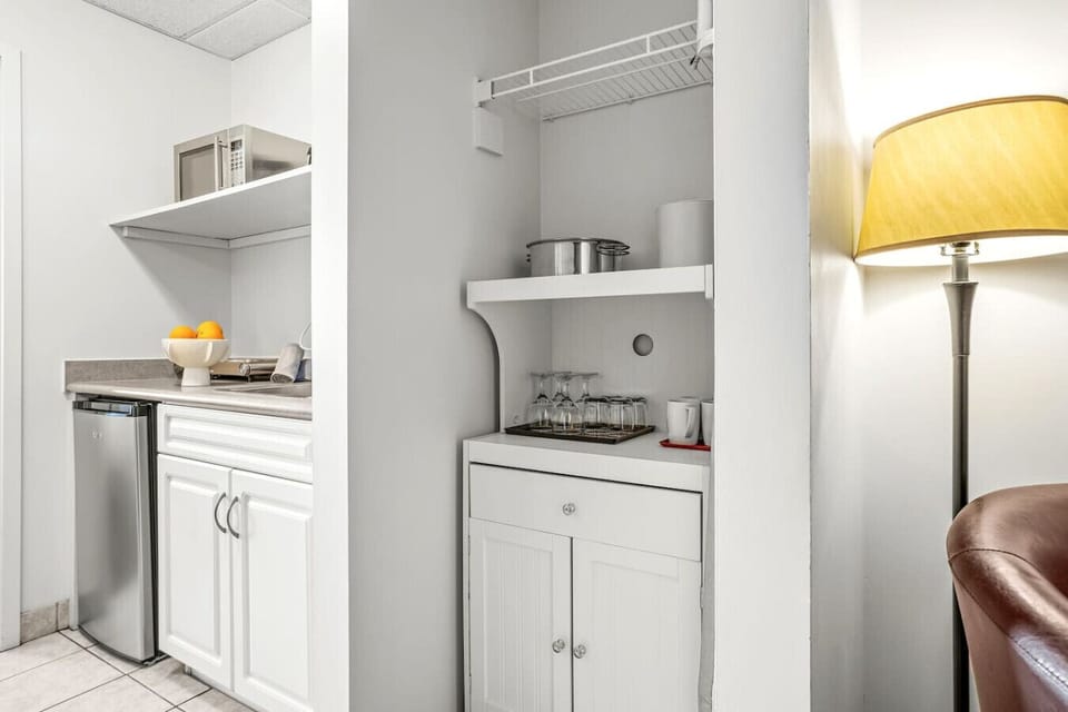 A compact kitchenette featuring a mini fridge, microwave, coffee maker, toaster, electric kettle, and essential kitchen essentials.