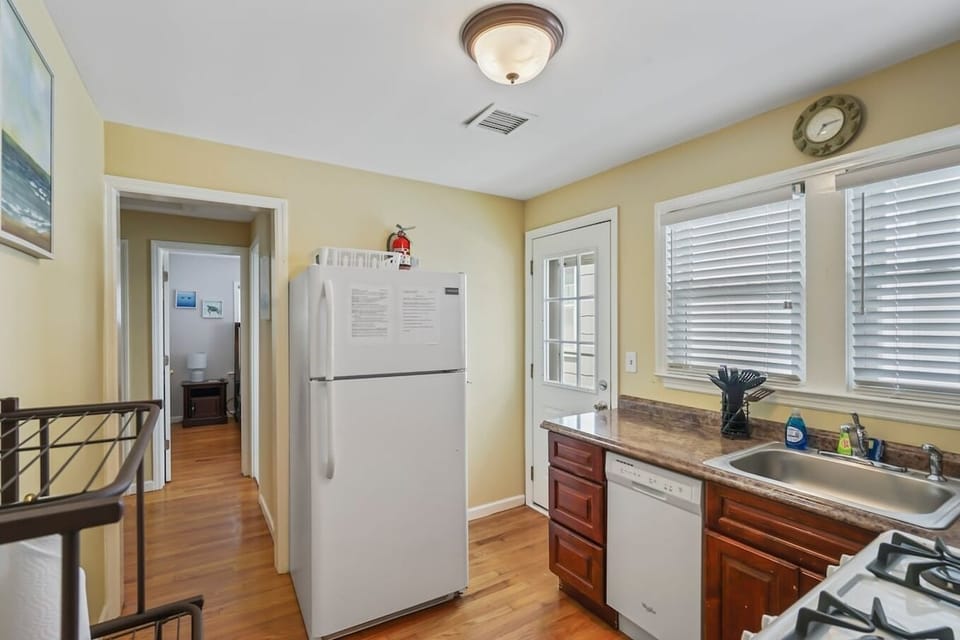 Prepare meals with ease in this convenient, fully-equipped kitchen, featuring essential white appliances like a full-size Frigidaire refrigerator and dishwasher. The classic wood cabinetry and abundant natural light create a cheerful atmosphere