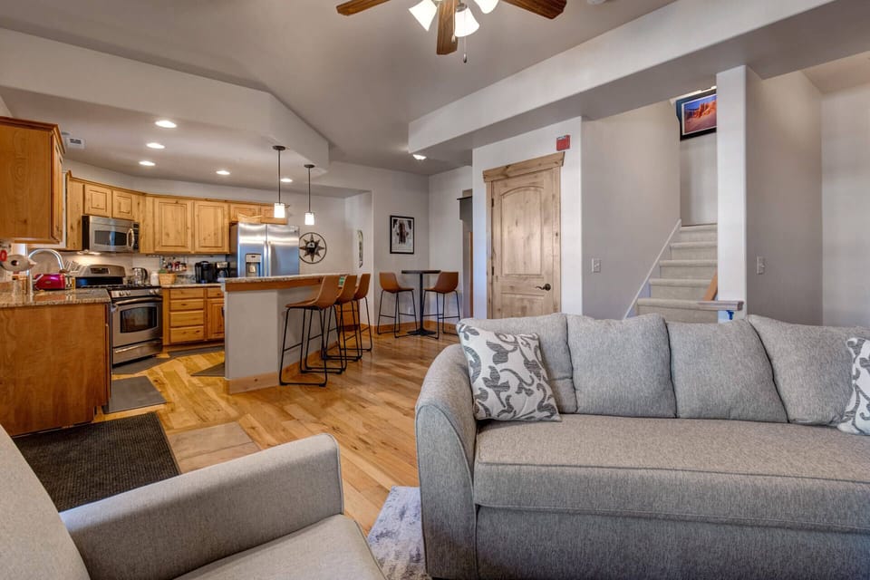 Unwind in your spacious open-concept living area, where soft gray sofas invite you to relax while gourmet meals await in the fully-equipped kitchen.