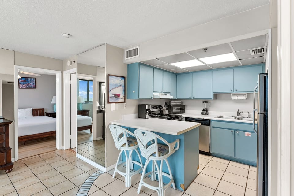 Compact kitchen with blue cabinetry and breakfast bar seating for two.