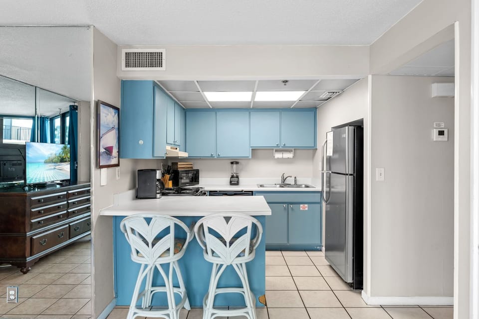 Compact kitchen with blue cabinetry and a breakfast bar for casual dining.
