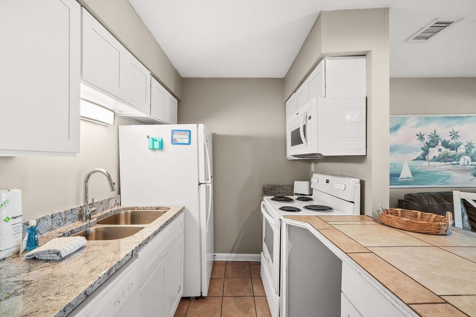 Compact kitchen with white appliances and granite countertops