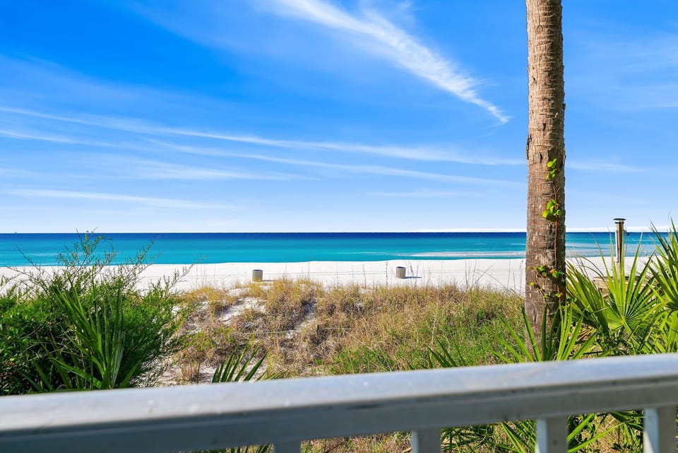 View of the beach and ocean from a balcony with tropical greenery