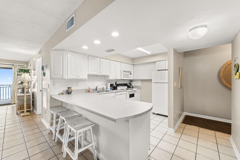 Modern kitchen with white cabinetry and a breakfast bar with seating.