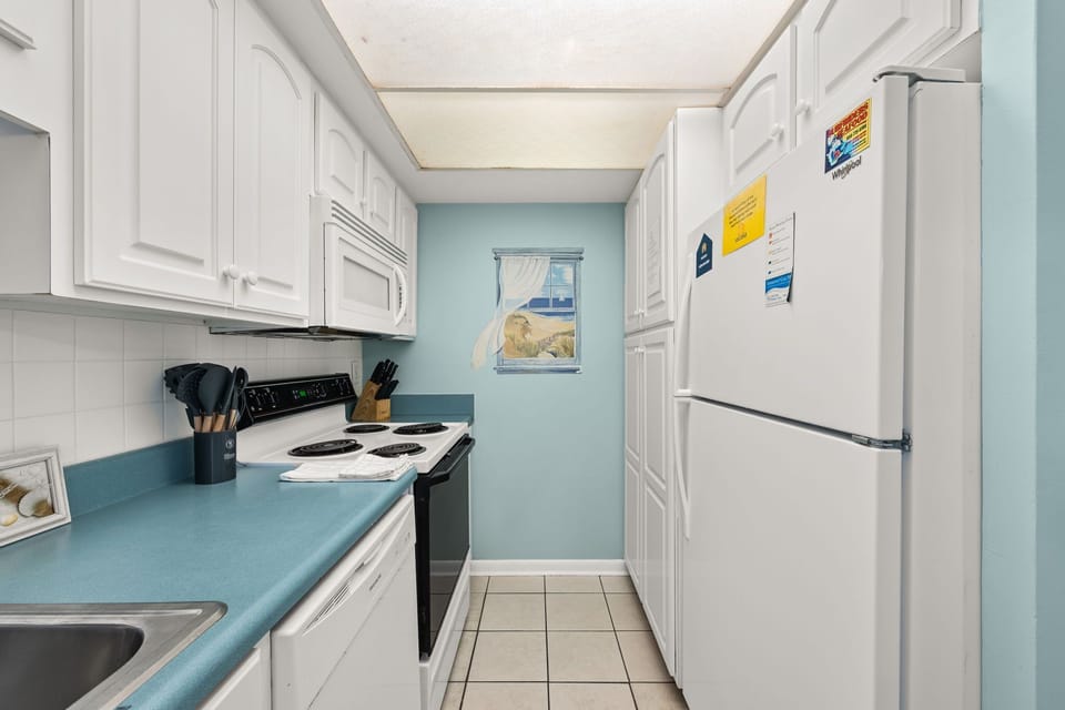 Compact kitchen with white cabinetry and blue countertops for a clean, functional space.