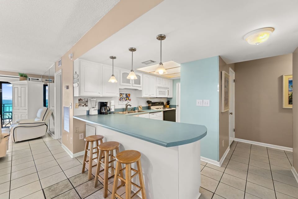 Open kitchen with a breakfast bar and seating for three in a bright, casual setting