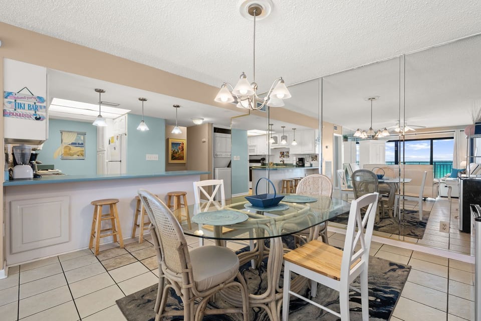 Dining area with glass table and ocean views in a bright, coastal-style space