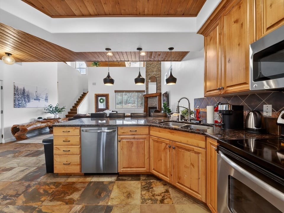 Your spacious kitchen features granite countertops, warm wood cabinets, and modern appliances perfect for preparing mountain getaway meals together.