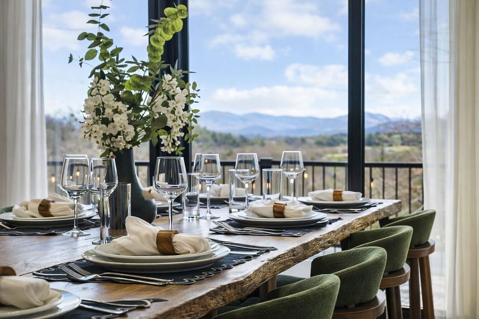 {Dining Area} Gather around a beautifully styled 12-person custom live oak dining table framed by panoramic mountain views. This inviting space is perfect for shared meals, celebrations, and memorable moments together.