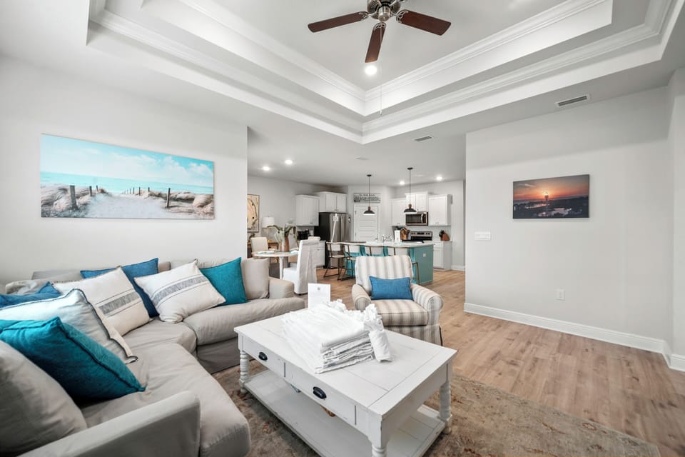 Relax in your bright, coastal-themed living room with comfy sectional seating and an open kitchen perfect for gathering.