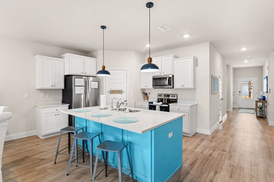 Cook up memories in this bright kitchen featuring a stunning turquoise island, modern appliances, and stylish pendant lighting.
