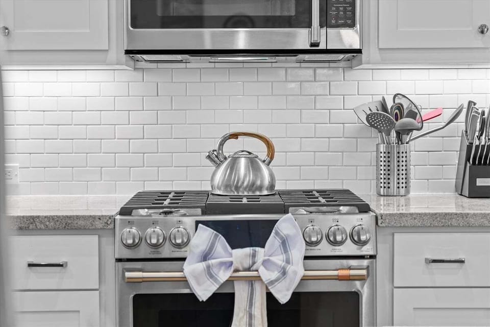 Stainless steel gas range with subway tile backsplash and modern cooking space for preparing vacation favorites.