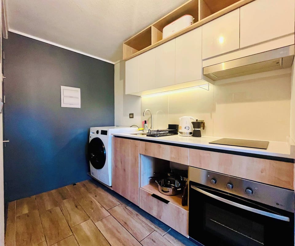 Sleek kitchen w/ open shelving, modern appliances & warm wood floors for easy home cooking.