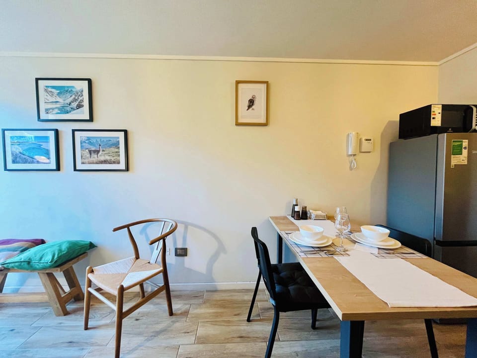 Bright dining area w/ a wooden table & wall art, ideal for relaxed meals or remote work.
