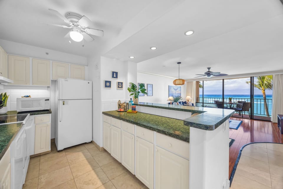 Appreciate the spacious kitchen with generous counter space, white cabinetry, and a clear line of sight to the living area and ocean views beyond.
