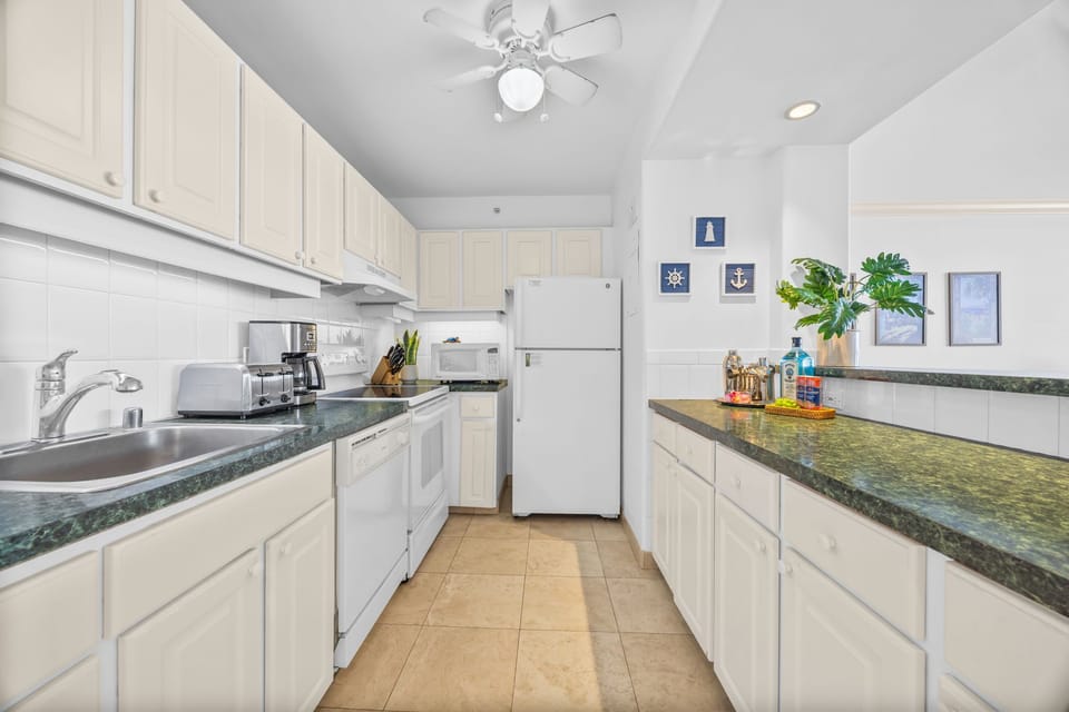 Enjoy the convenience of a fully equipped kitchen featuring white cabinetry, generous counter space, and a clean, airy coastal design.
