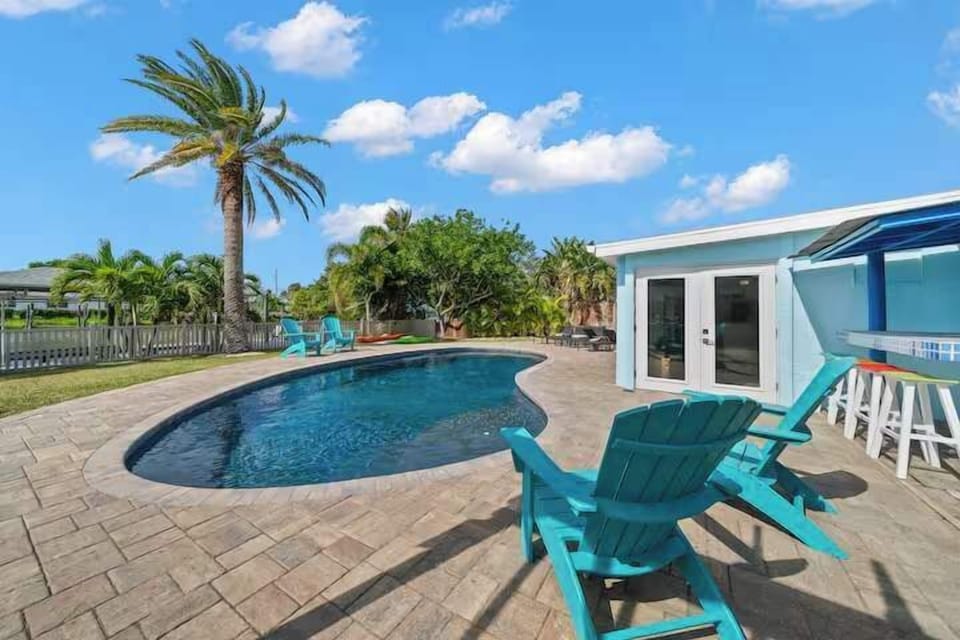 Relax by the curved pool with tropical landscaping and a poolside bar area.
