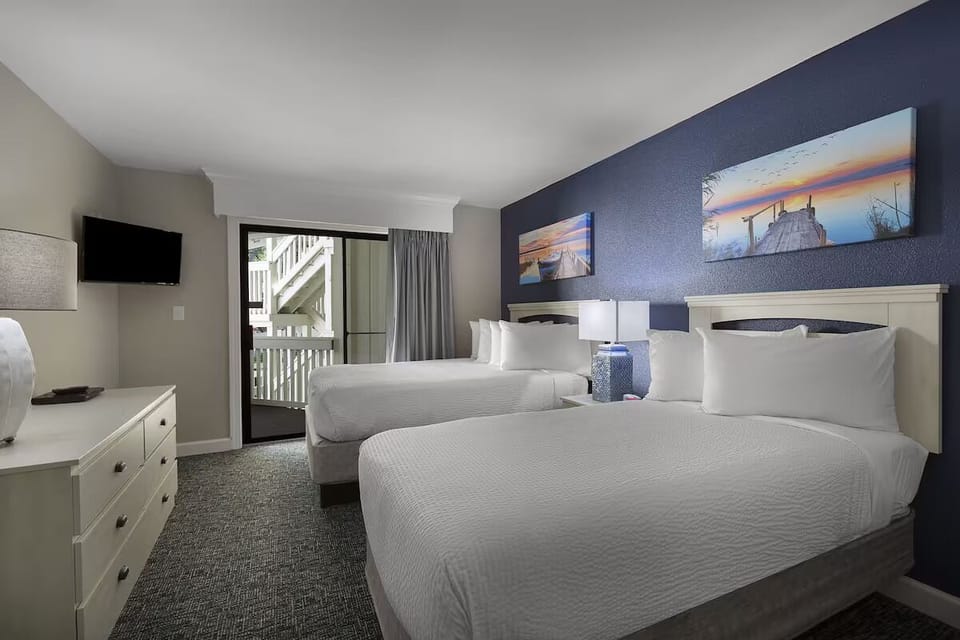 Unwind in crisp bedding with balcony breeze nearby.
