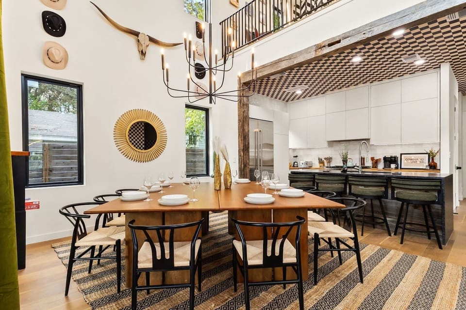 The chef-style kitchen features a large island, stainless appliances, and complete cookware—perfect for group meals around the massive dining table.
